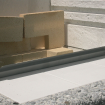 Usazení ochranného nerezového plechu na hraně topeniště